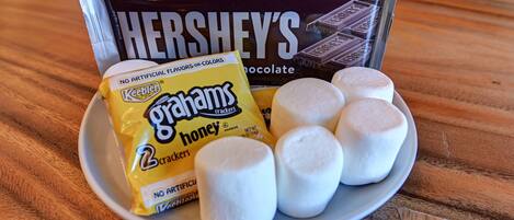 A plate with marshmallows, a pack of Ghirayams crackers, and a Hershey's chocolate bar.