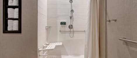 A walk-in shower with a glass door, a towel rack with folded towels, and a handheld showerhead.