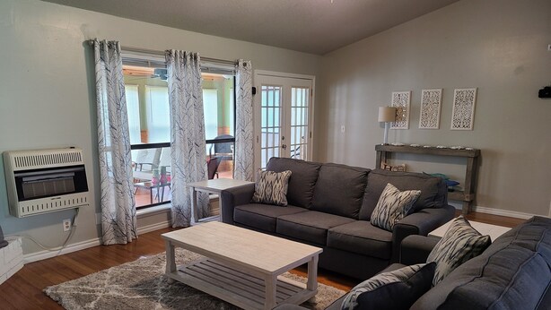 A living room with a gray sofa, a wooden coffee table, and a patterned rug. - Beautiful Lake Front home w/ sunroom and outdoor patio, (Stigler)