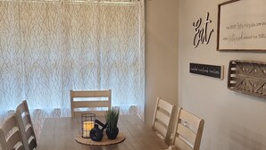 A dining area with a wooden table, six chairs, a chandelier, and decorative wall art. - Beautiful Lake Front home w/ sunroom and outdoor patio, (Stigler)