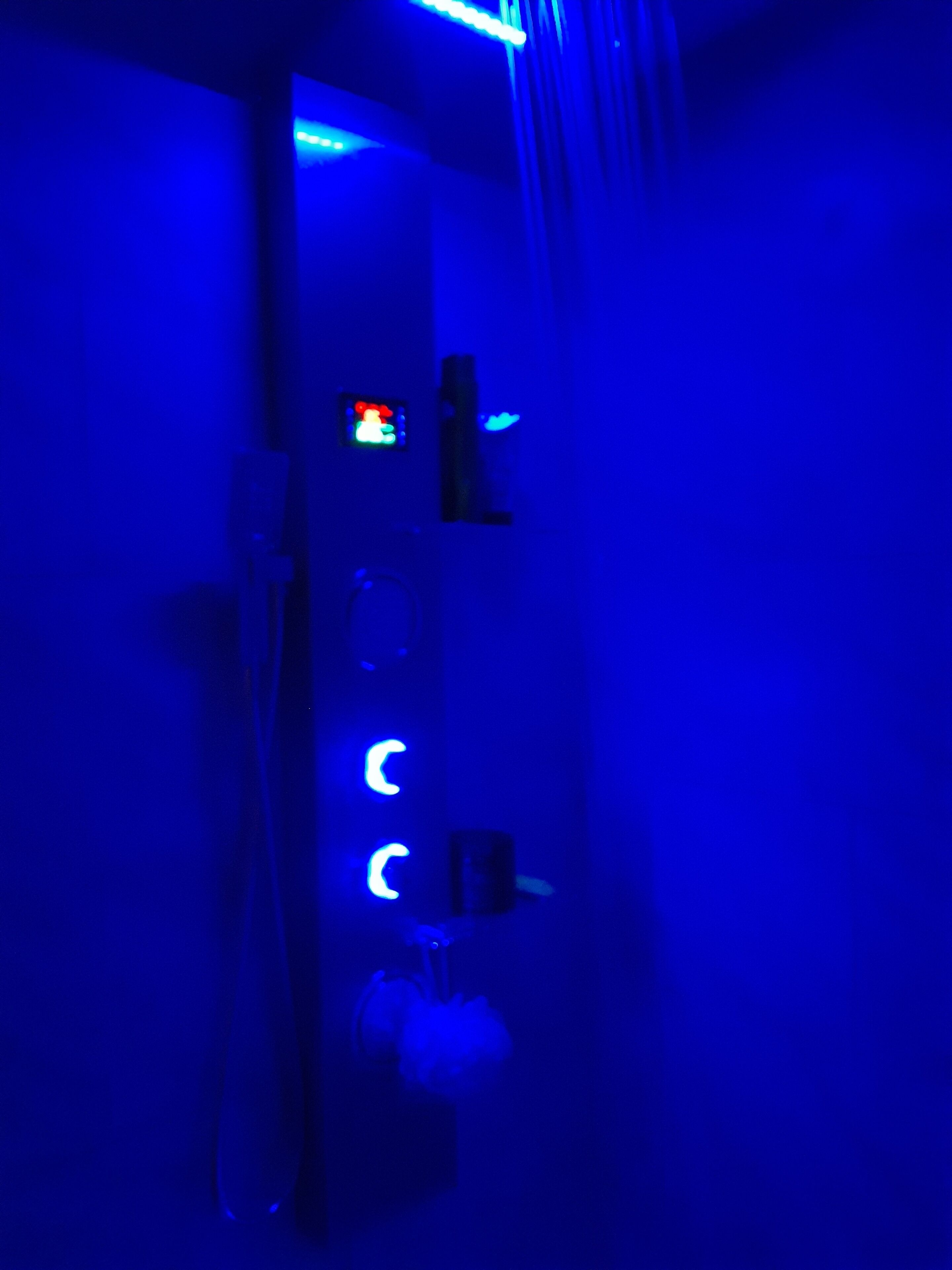 A dimly lit room with a blue hue, a small illuminated control panel, and a door handle.