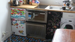 Una cocina con encimera de madera, un refrigerador con imanes, una lavadora y una ventana sobre el fregadero.