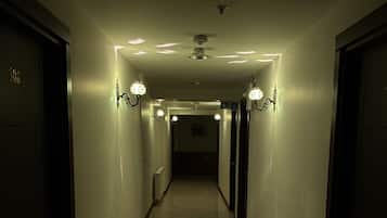 Un pasillo con piso de baldosas brillantes, paredes con luces y puertas a ambos lados.