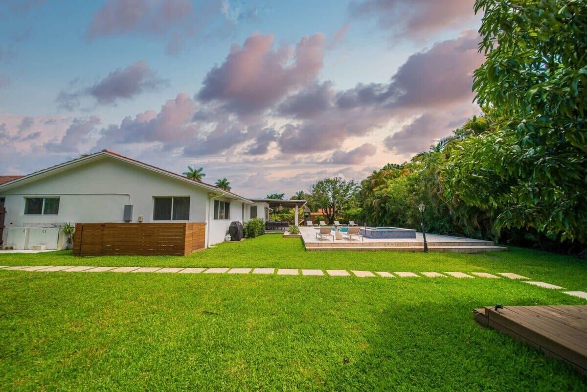 Uma casa moderna com gramado bem cuidado, piscina e deck de madeira.