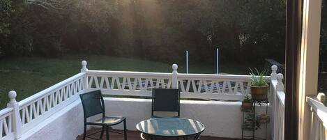 Una terraza de madera con dos sillas y una mesa, rodeada por una barandilla blanca.