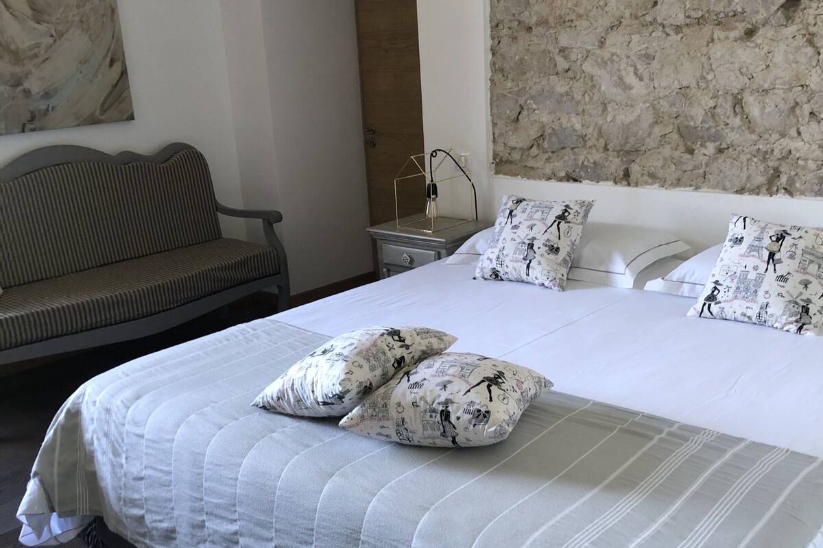 Un dormitorio ordenado con una cama grande, un sofá y un cuadro en la pared.