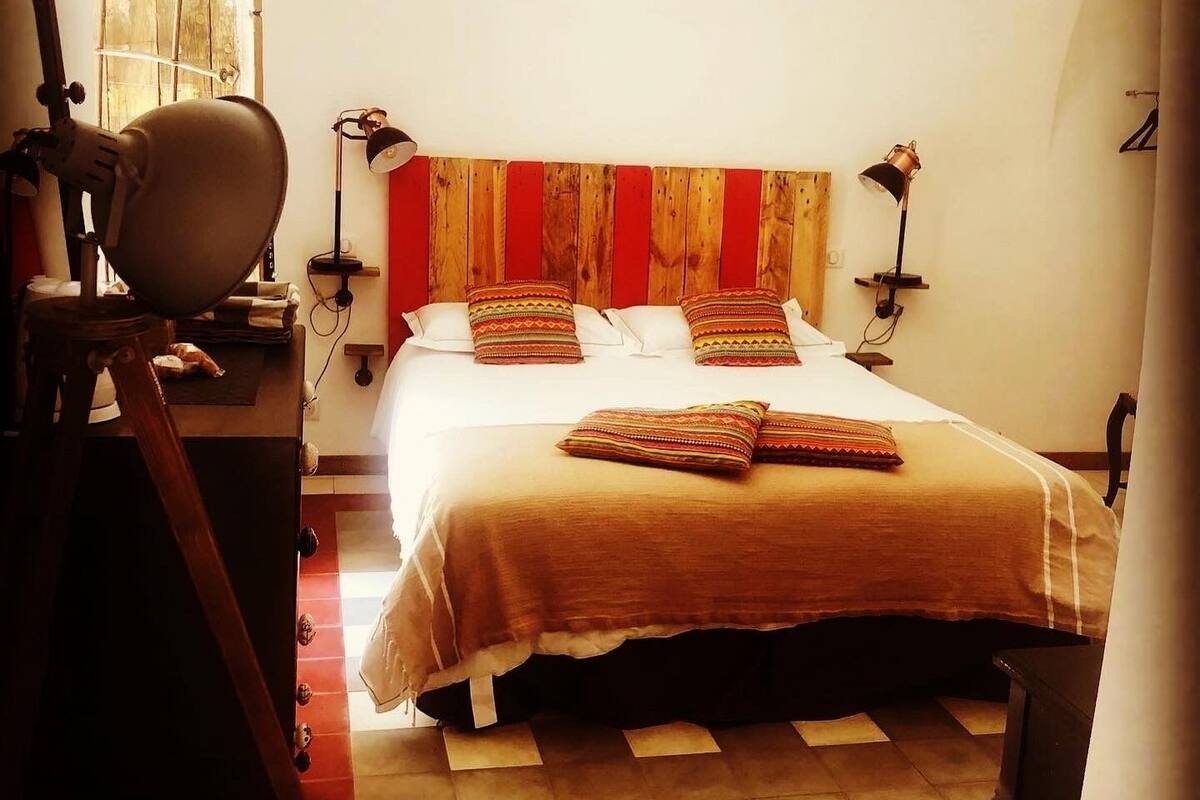 Un dormitorio con una cama, dos lámparas de noche, un escritorio con una silla y una ventana con cortinas.