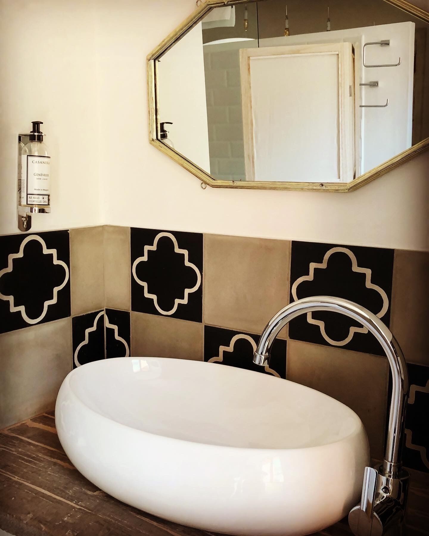 Une salle de bain avec un lavabo blanc, un robinet chromé et un miroir au-dessus.