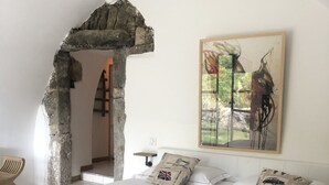 Un dormitorio con una cama grande, un arco de piedra, un cuadro y vistas a un jardín.