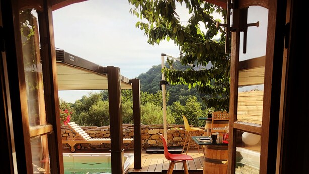 Terraza de madera con jacuzzi, sillones de descanso y pared de piedra.