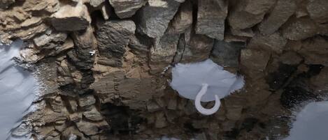 Primer plano de una pared de piedra con textura, con un objeto blanco colgando.