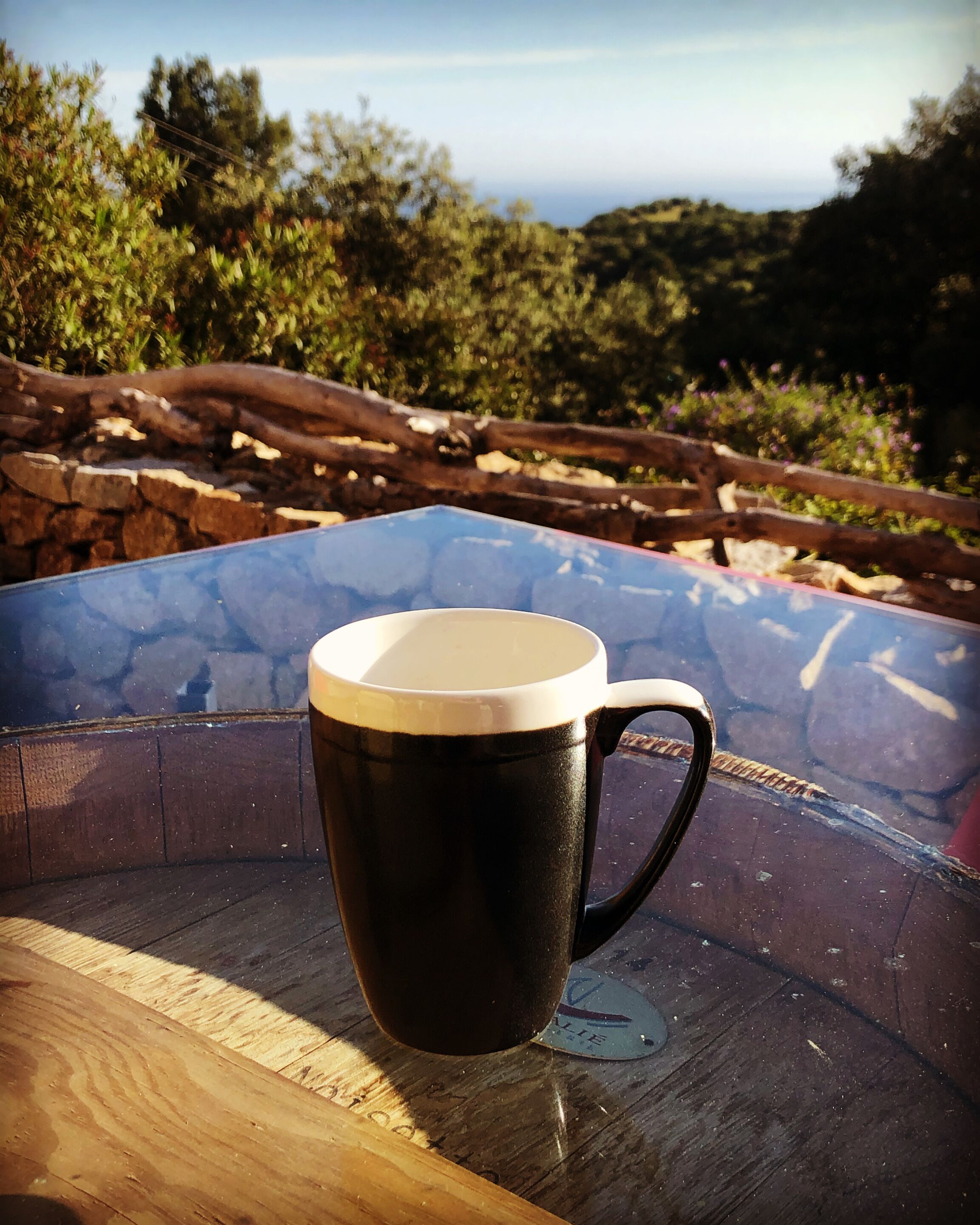 Een zwarte mok met witte binnenkant op een houten tafel.