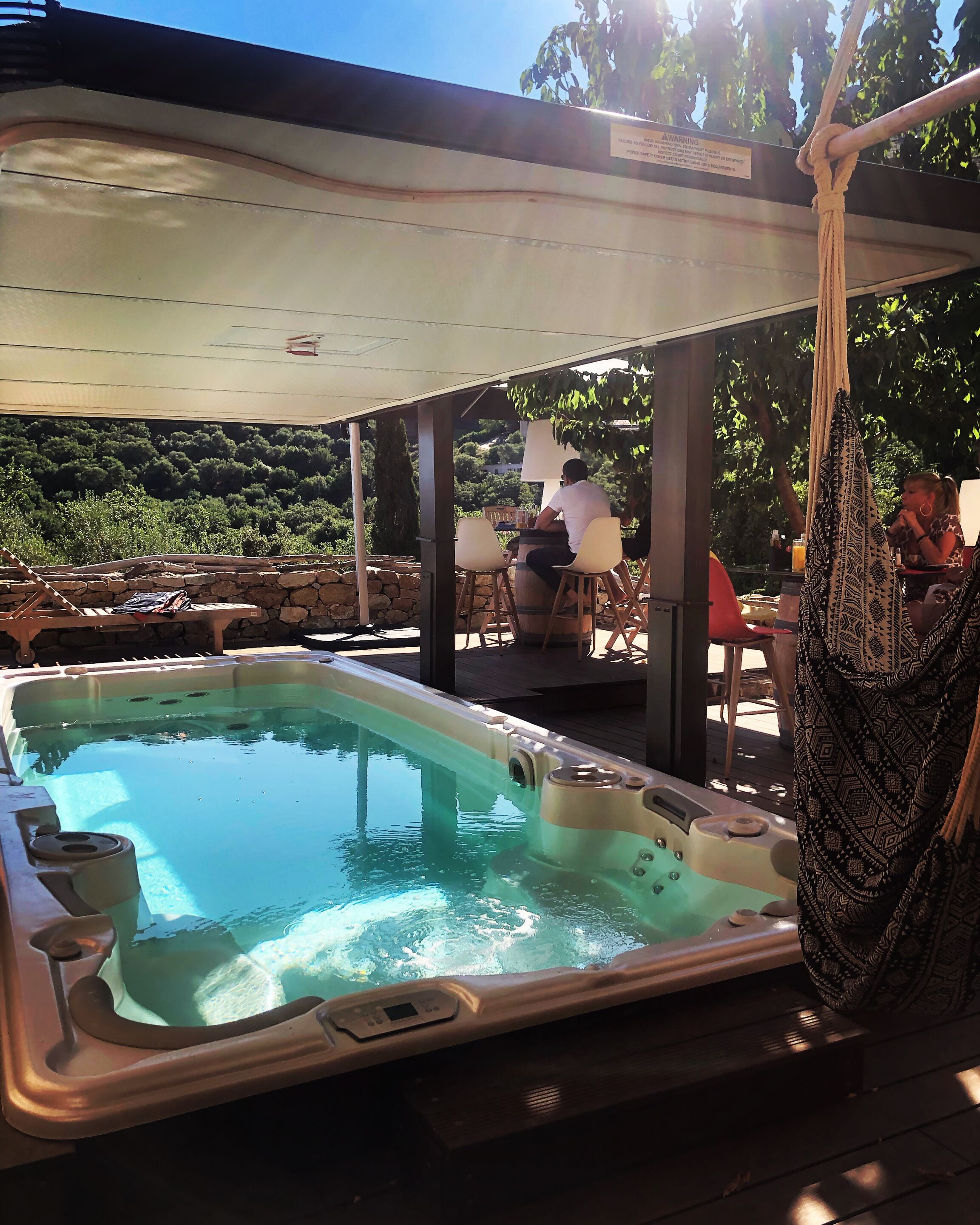 Ein Whirlpoolbereich mit Pool, Sitzgelegenheiten im Freien und einem Sonnensegel.