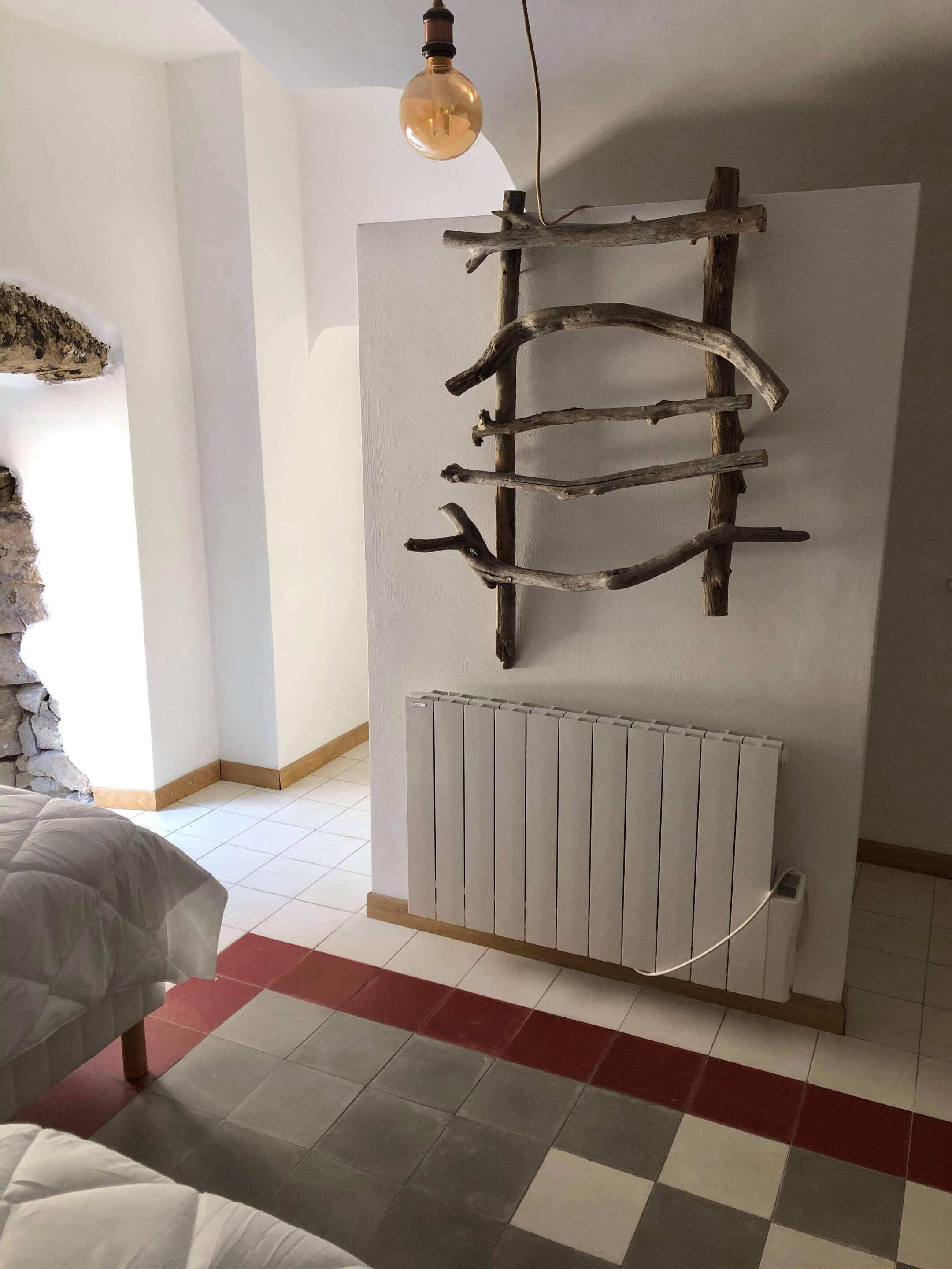 Une pièce comprenant un lit, un radiateur et une étagère en bois fixée au mur.