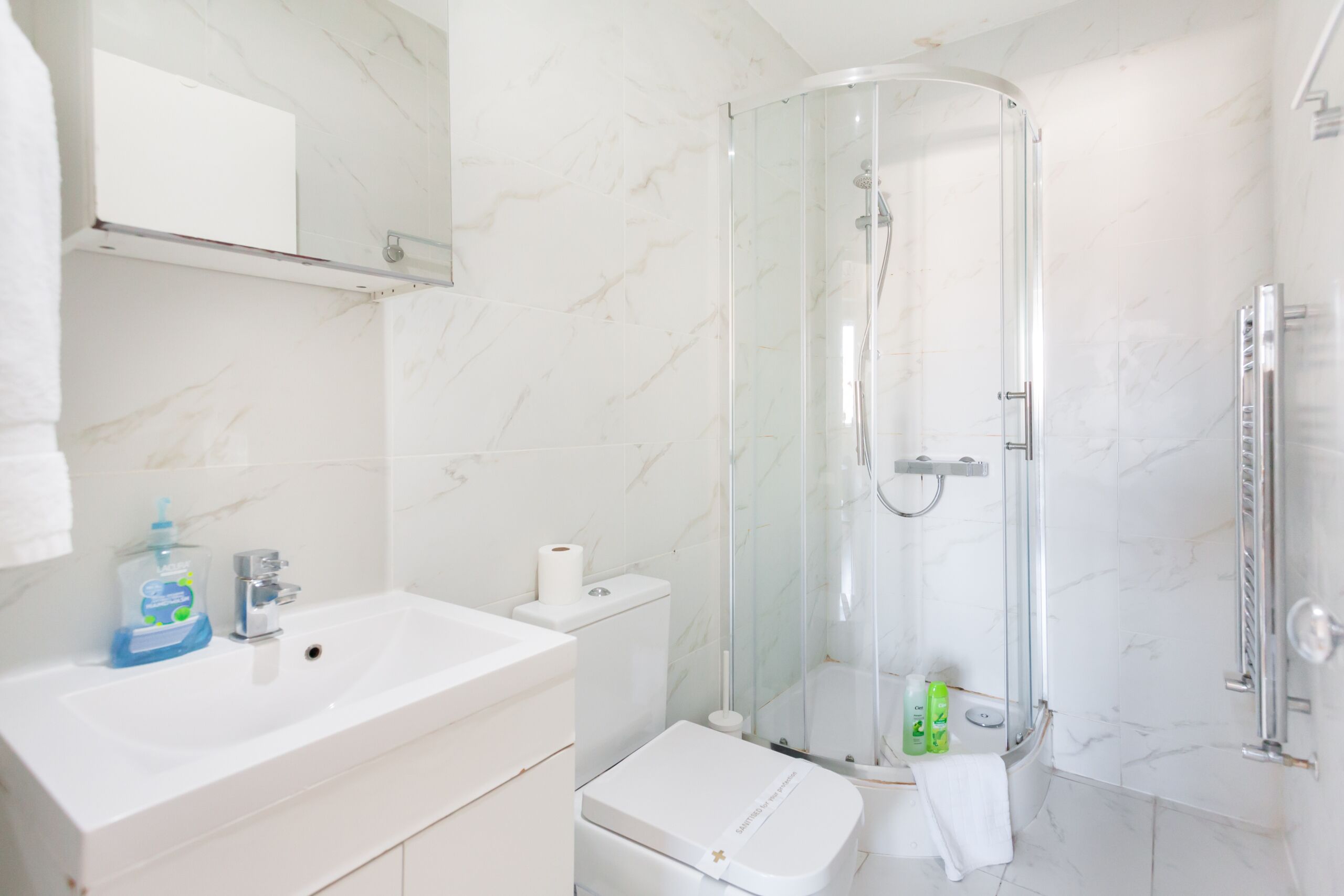 Un baño moderno con ducha envuelta en vidrio, un lavabo blanco y un inodoro.