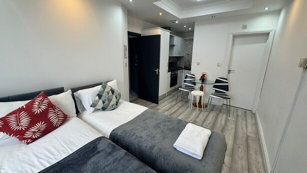 Une chambre d’hôtel moderne avec deux lits, une petite kitchenette et un coin repas.