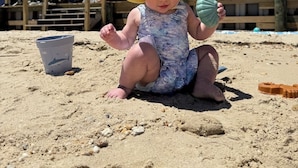 Un enfant joue sur la plage avec un seau et un jouet.