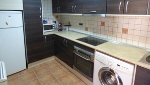 A kitchen with dark wooden cabinets, a white refrigerator, a microwave, an oven, a dishwasher, and a gas stove.