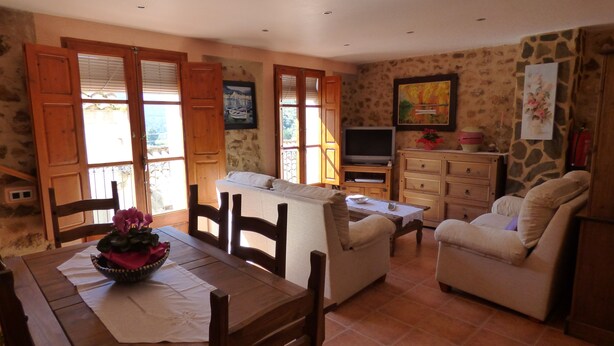 A cozy living room with a wooden dining table, a sofa, and a television.