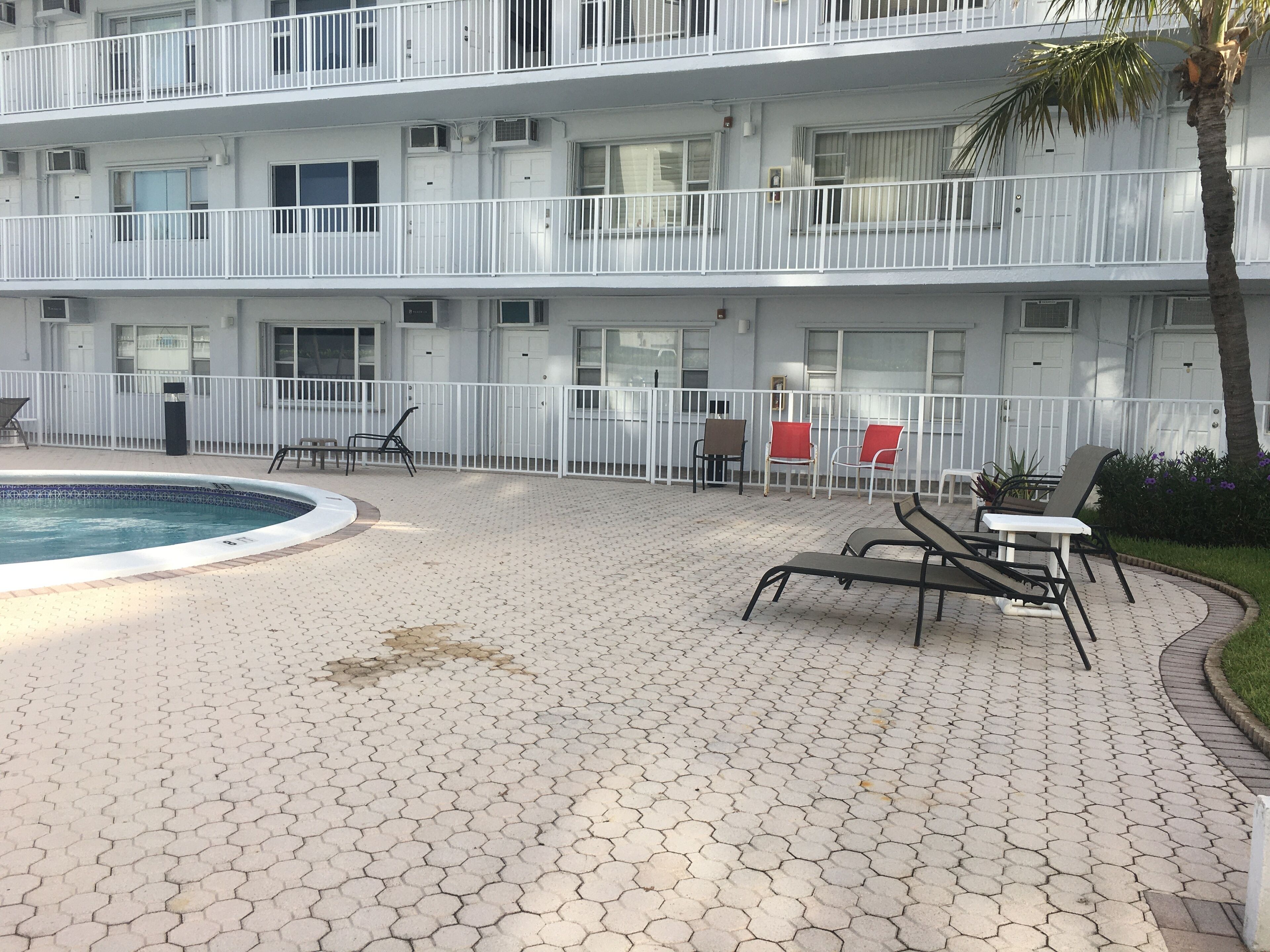 Ein mehrstöckiges Hotel mit Poolbereich, Sitzgelegenheiten im Freien und einem umzäunten Balkon.