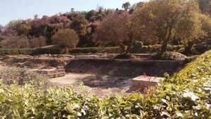 Un sitio arqueológico con estructuras de piedra y jardines en terrazas.