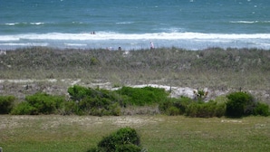 Un paysage côtier avec une plage, des dunes herbeuses et l’océan.