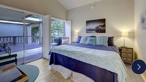 A bedroom with a bed, a nightstand, a lamp, and a view of the outside deck. - Incredible waterfront! Relaxing!- Swim & Fish, Pool Access (Point Venture)