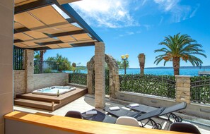 Una terraza en la azotea con jacuzzi, sillones de descanso y vistas al mar.