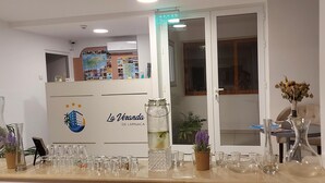 Un espace d’accueil d’hôtel avec un comptoir où sont exposés divers objets en verre et une plante en pot.