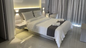 A modern hotel room with a large bed, bedside tables, a nightstand, and a window with curtains. - La Veranda Hotel (Larnaca)