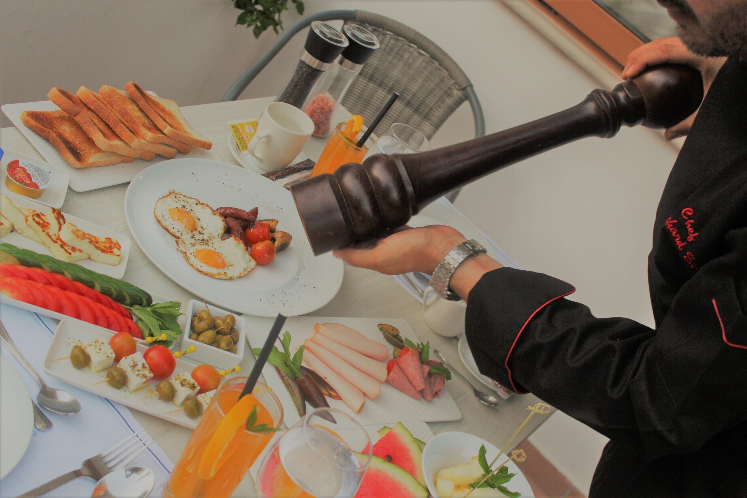 A breakfast setting with various dishes, a pepper mill, and dining utensils on a table.