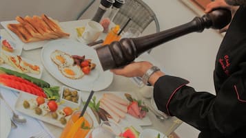 Uma mesa posta para o café da manhã, com diversos pratos, um moedor de pimenta e utensílios de jantar.
