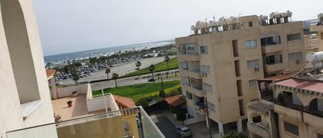 A residential building with multiple balconies, a view of the beach, and parked cars.