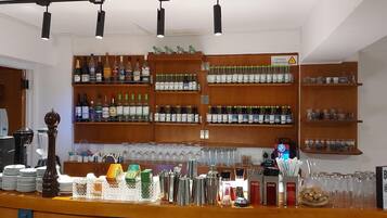 A bar area with shelves of liquor bottles, glasses, and a sign indicating breakfast for 8 euros.
