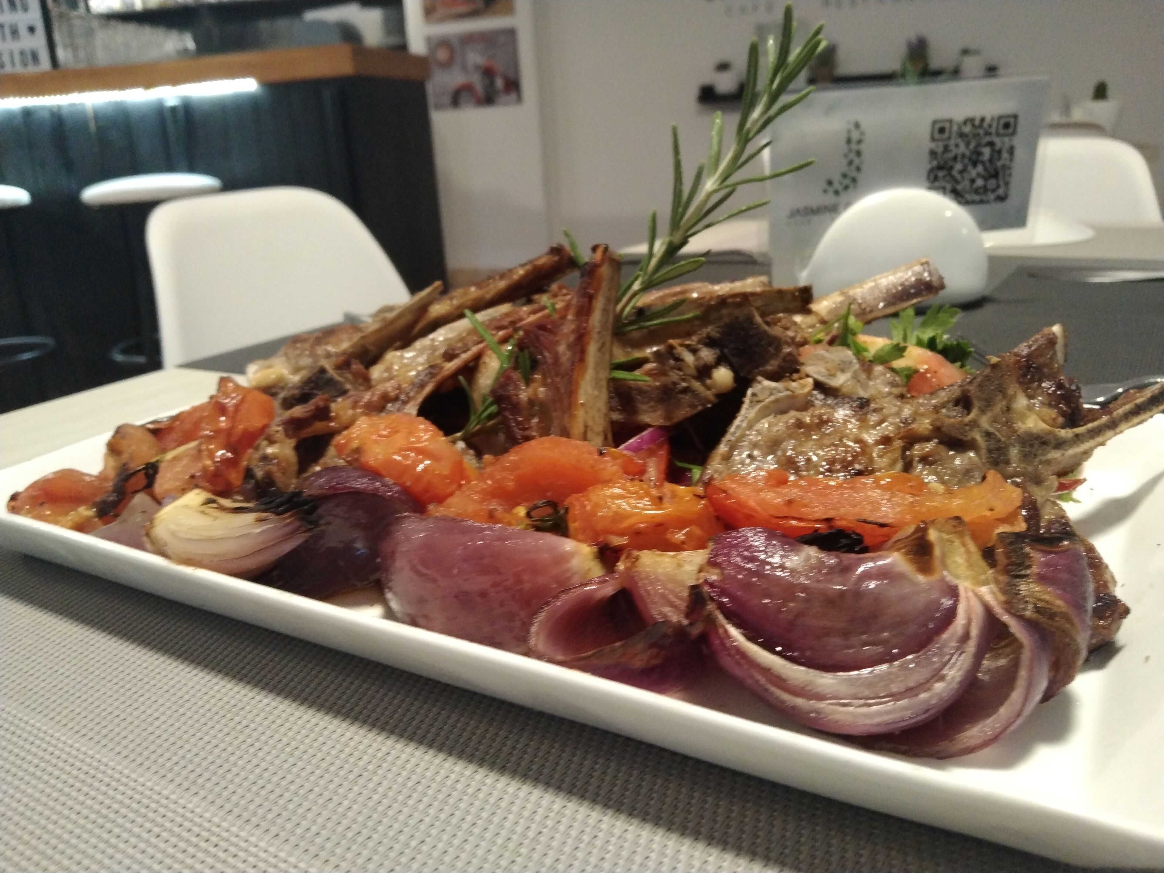 A plate of roasted lamb with vegetables on a white plate.