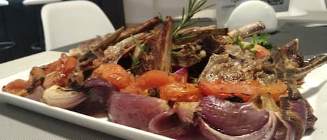 A plate of roasted lamb with vegetables on a white plate.