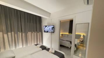 A hotel room with two beds, a television, a mirror, and a telephone.