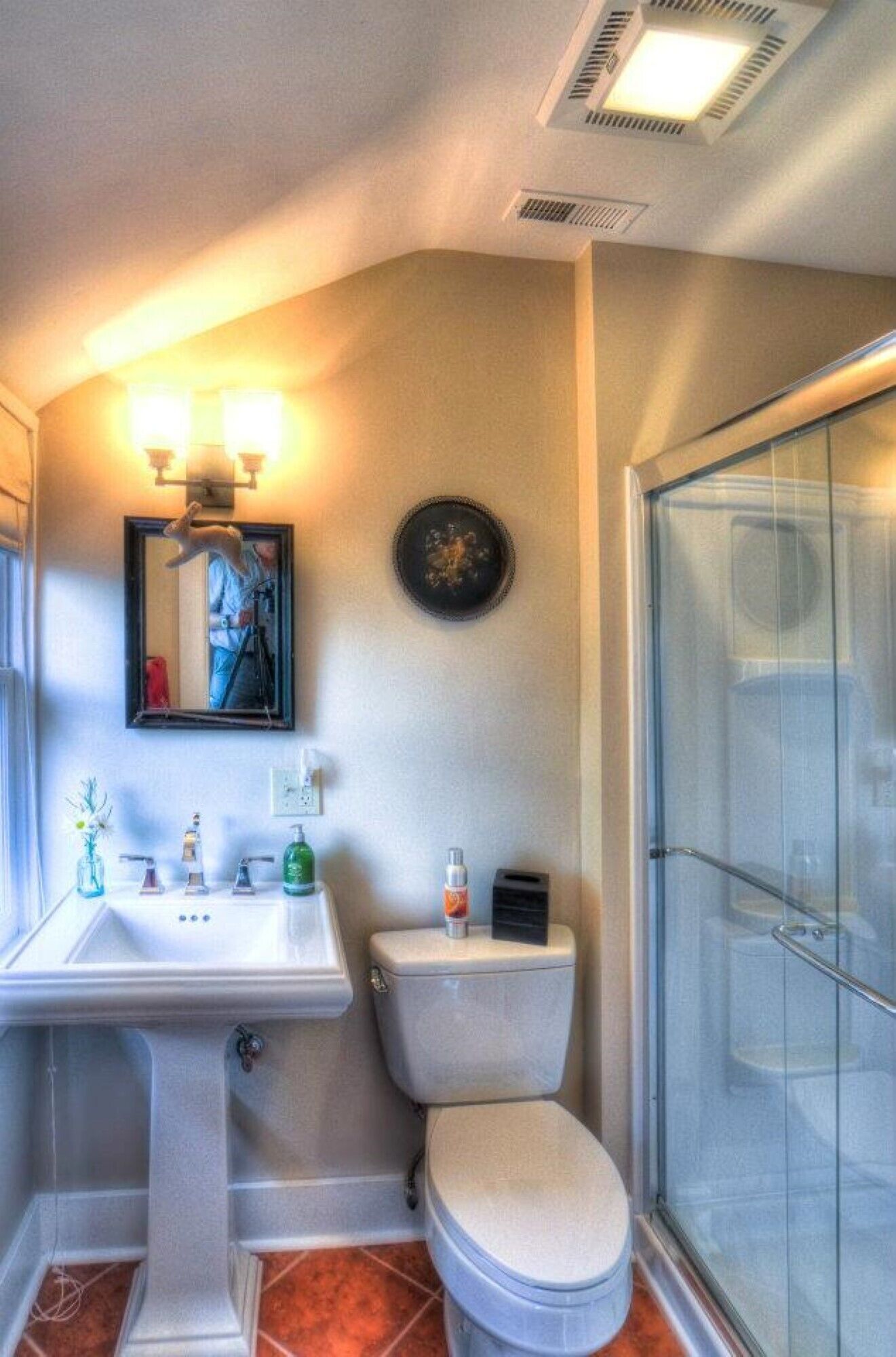 A bathroom with a pedestal sink, toilet, and a glass shower enclosure.