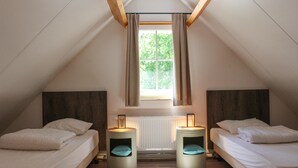 Une chambre avec deux lits, une fenêtre avec des rideaux, un radiateur et deux lampes de chevet.