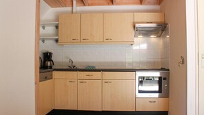 Une cuisine compacte avec des meubles en bois, un four encastré et une machine à café.