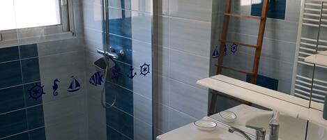 Een badkamer met een douche, wastafel en spiegel.