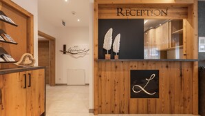 Un mostrador de recepción con acabado de madera, un cartel que dice "RECEPTION" y un letrero en la pared con la palabra "JETZT".