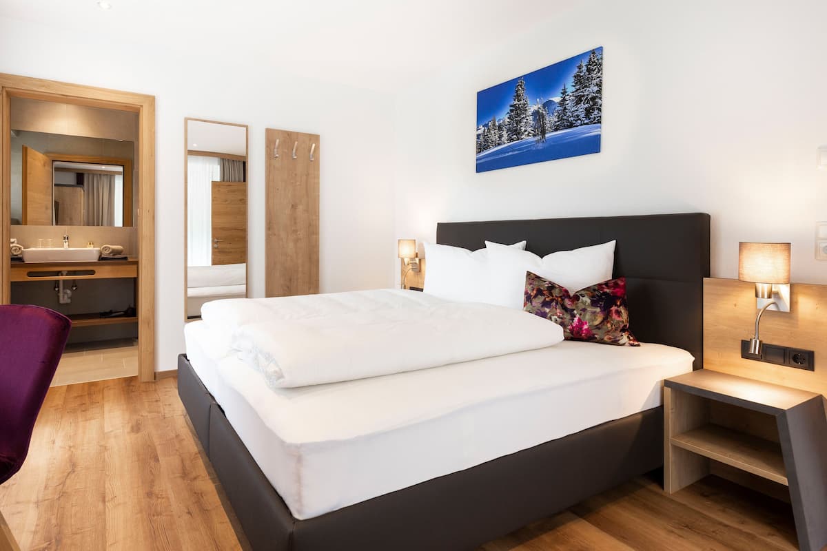 Ein Hotelzimmer mit Bett, Schreibtisch, Stuhl, Bad und einem Wandbild.