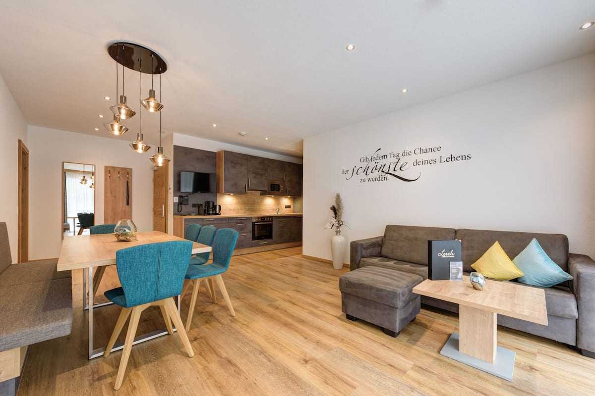 Ein modernes Wohnzimmer mit Essbereich, einer Sofagarnitur und einer Küche im Hintergrund.