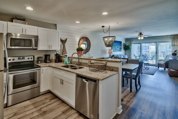 A modern kitchen with stainless steel appliances, a dishwasher, and a dining area with a view.
