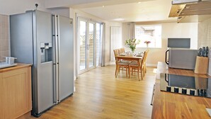 Una cucina moderna con frigorifero integrato, un'area pranzo con tavolo e sedie e un'isola centrale con forno a microonde e utensili.
