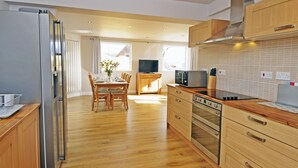 Una cucina moderna con mobili in legno, elettrodomestici in acciaio inossidabile e un'area pranzo con tavolo e sedie in legno.