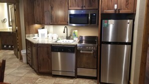 A kitchen with wooden cabinets, stainless steel appliances, a microwave, a refrigerator, a dishwasher, and a stove.