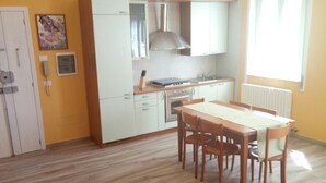 Une cuisine de taille réduite avec des meubles blancs, un four encastré et une fenêtre agrémentée de rideaux.