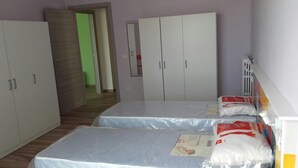 Une chambre avec deux lits, une armoire et un radiateur.